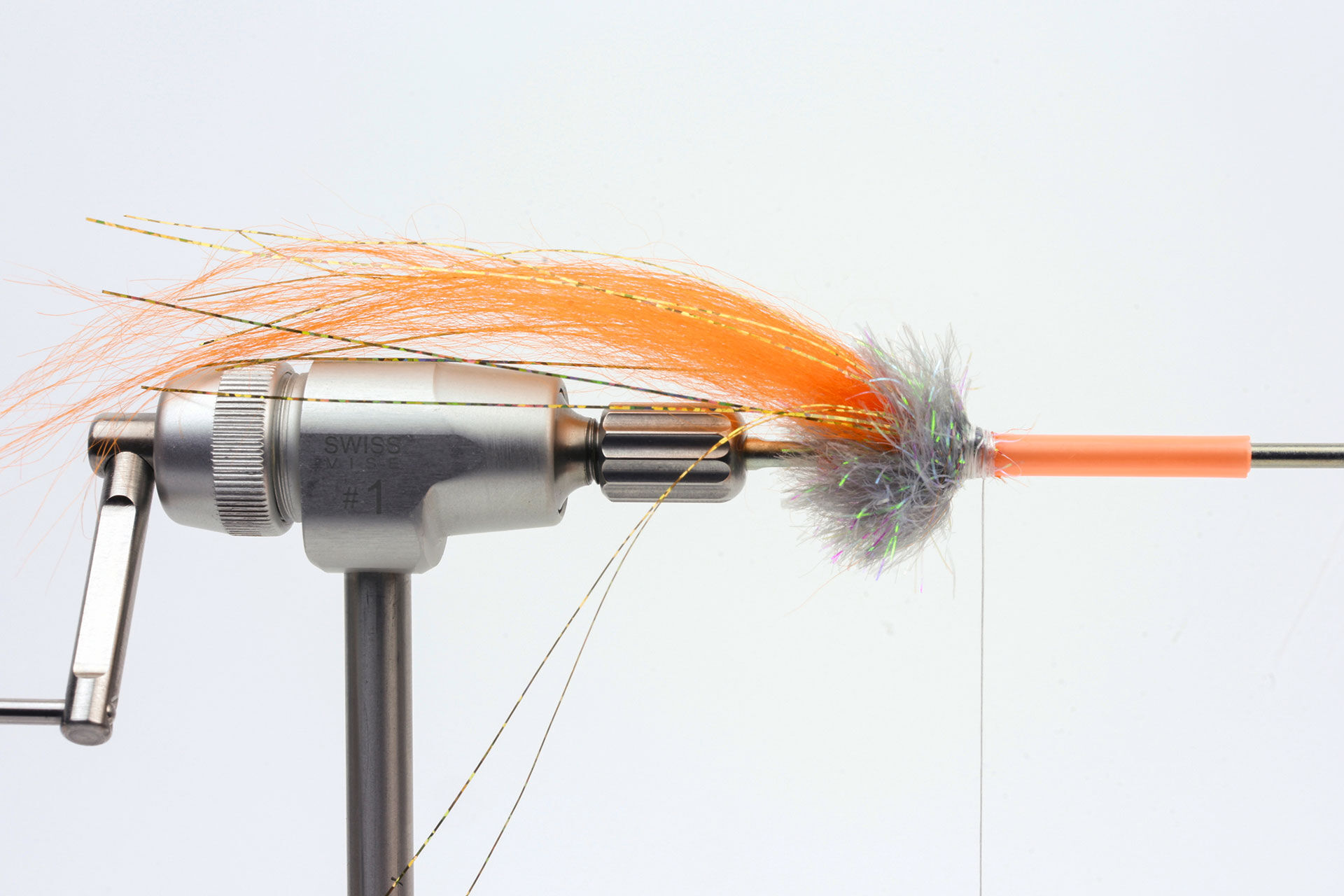  2. Binde einen Büschel Pike Monkey Streamer Hair ein, dann etwas Glitzermaterial  und lege eine zweite Wicklung Chenille darüber.  