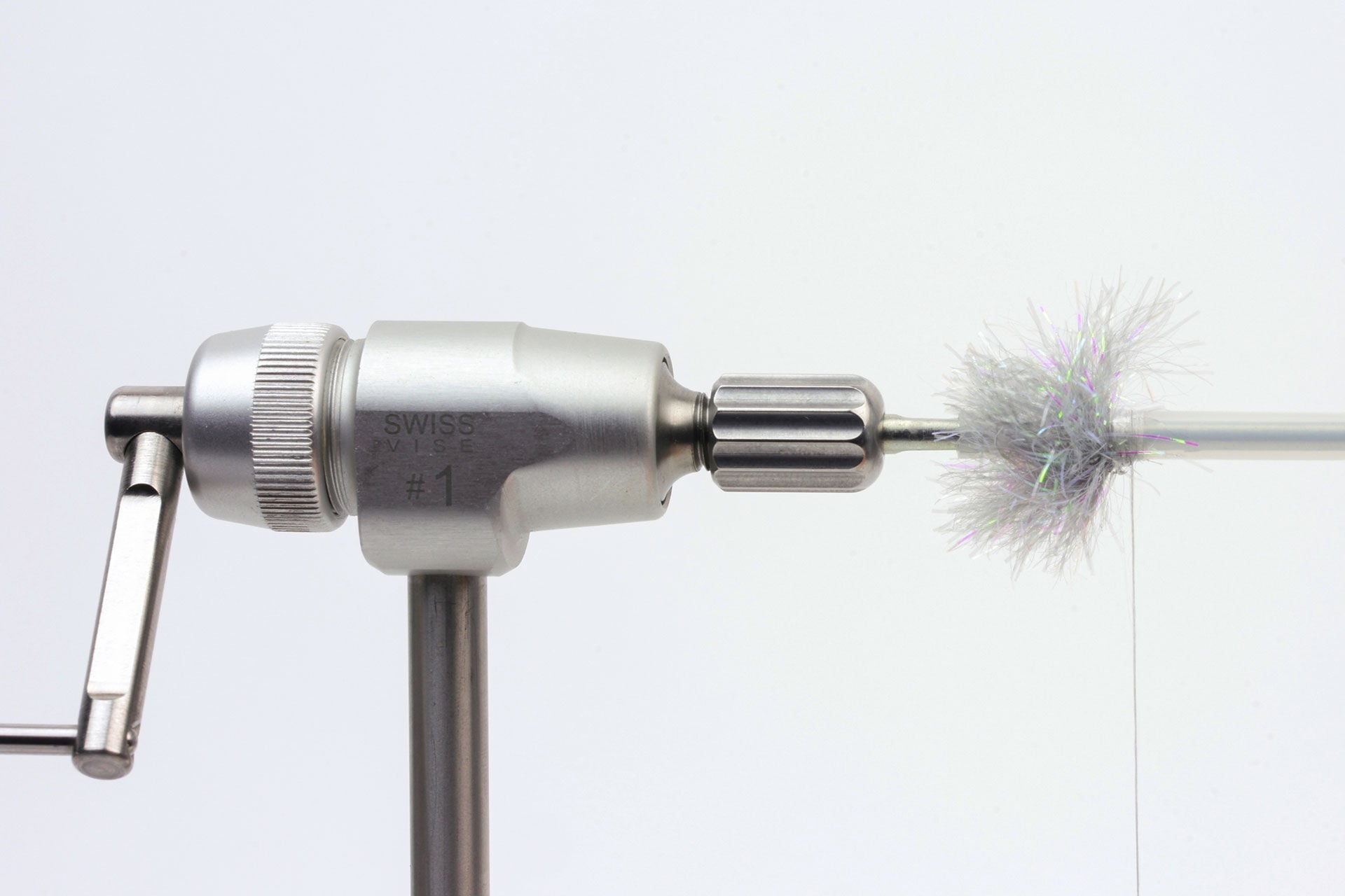  1. Nimm eine Tube, schneide sie auf die gewünschte Länge und befestige sie auf einer konisch geformten Nadel. Setze den Bindefaden auf und sichere ihn mit Lack. Binde die Chenille ein und wickle sie mehrmals um die Tube. Der Vorteil einer dickeren Tube ist, dass viele grosse Haken gut in die Öffnung passen. Ist das Hakenöhr dennoch zu gross, kannst Du einen Hook Guide verwenden.  