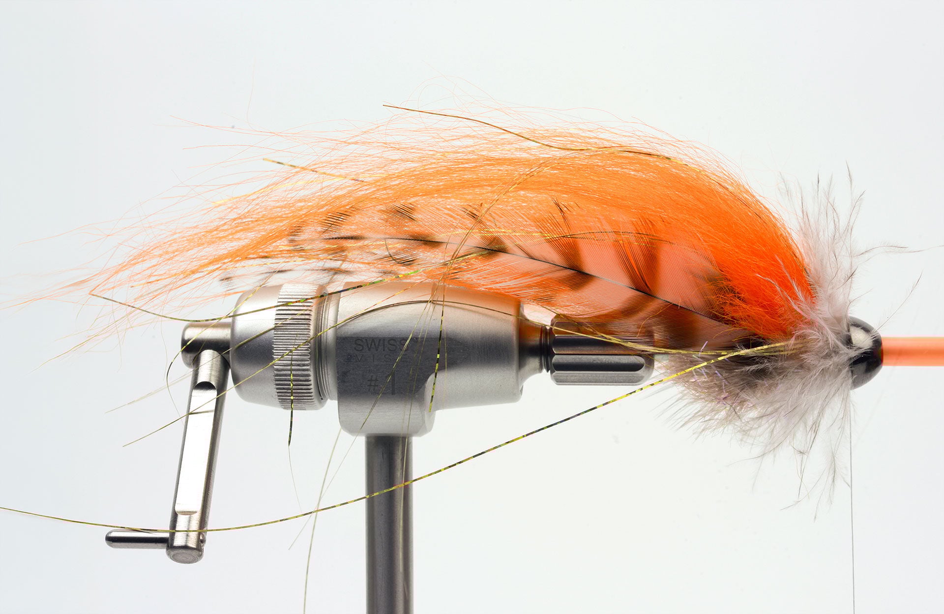  7. Zum Schluss bindest Du einen Hechelkragen ein, damit die Cone sauber am Material anliegt. Ich habe hier Chickabou verwendet (flaumige Unter­federn eines Whiting Saddle). Alternativ kannst Du Haare oder Marabou nehmen. Schiebe anschliessend die Cone auf die Tube, kürze die Tube und schmelze das Ende leicht an, damit die Cone an Ort und Stelle bleibt. Optional kannst Du noch Augen aufkleben.  Ich wünsche Dir viel Spass beim Binden dieses Musters – und fangen wirst Du damit garantiert!  